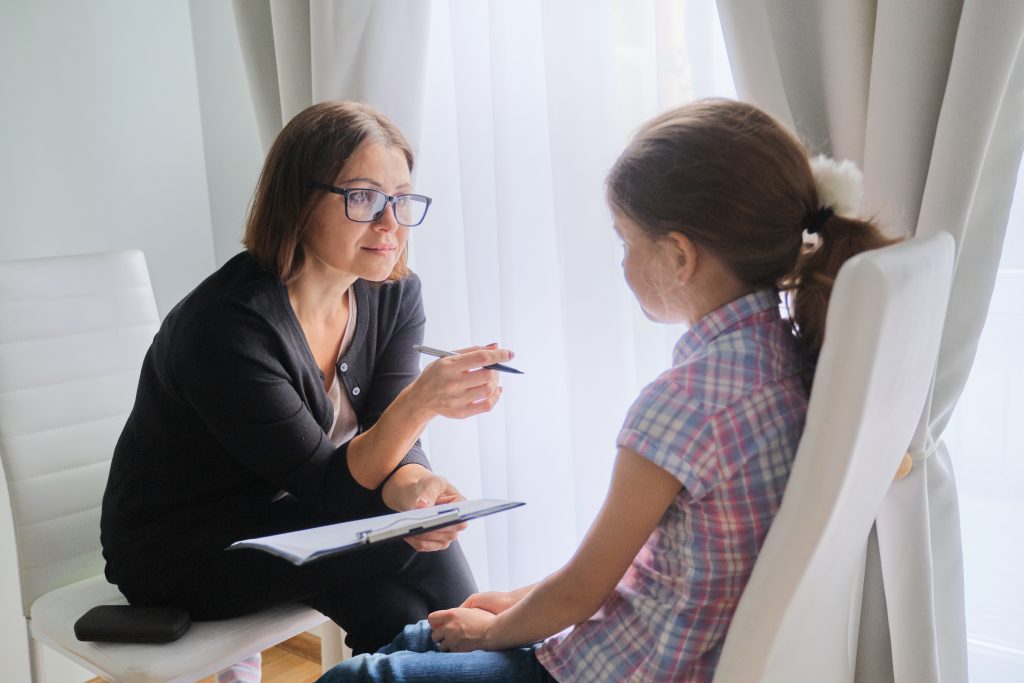 Talking girl and woman corporate trustee in office near window
